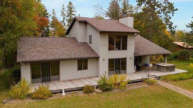 rear view of house featuring a lawn, a hot tub, and a deck