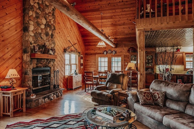 living room with high vaulted ceiling, a stone fireplace, wood walls, beam ceiling, and hardwood / wood-style floors