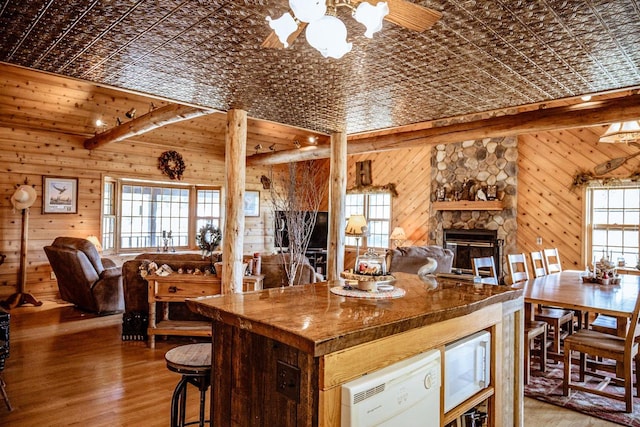 kitchen with wooden walls, hardwood / wood-style floors, plenty of natural light, and white microwave