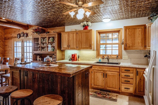 kitchen with wooden walls, ceiling fan, plenty of natural light, and sink