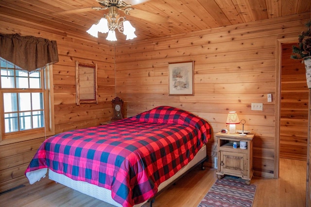 bedroom with wood ceiling, wooden walls, ceiling fan, and hardwood / wood-style flooring