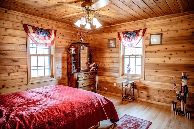 bedroom featuring light hardwood / wood-style flooring, wood ceiling, wood walls, and ceiling fan