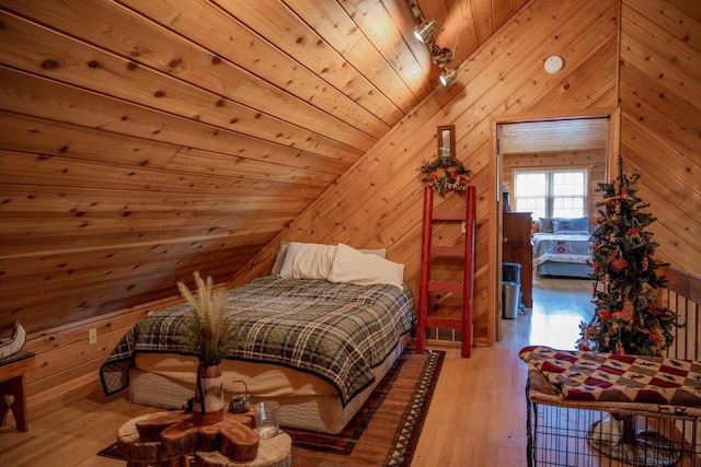 bedroom with wooden walls, light wood-type flooring, vaulted ceiling, and wooden ceiling