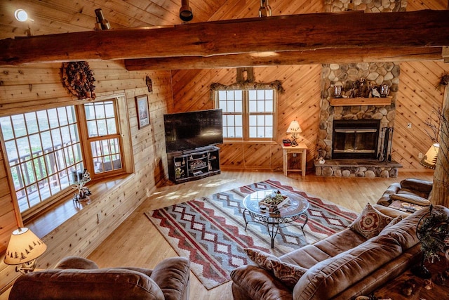 living room with wood ceiling, beam ceiling, a stone fireplace, wooden walls, and hardwood / wood-style flooring