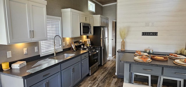 kitchen featuring appliances with stainless steel finishes, white cabinets, dark hardwood / wood-style flooring, ornamental molding, and sink