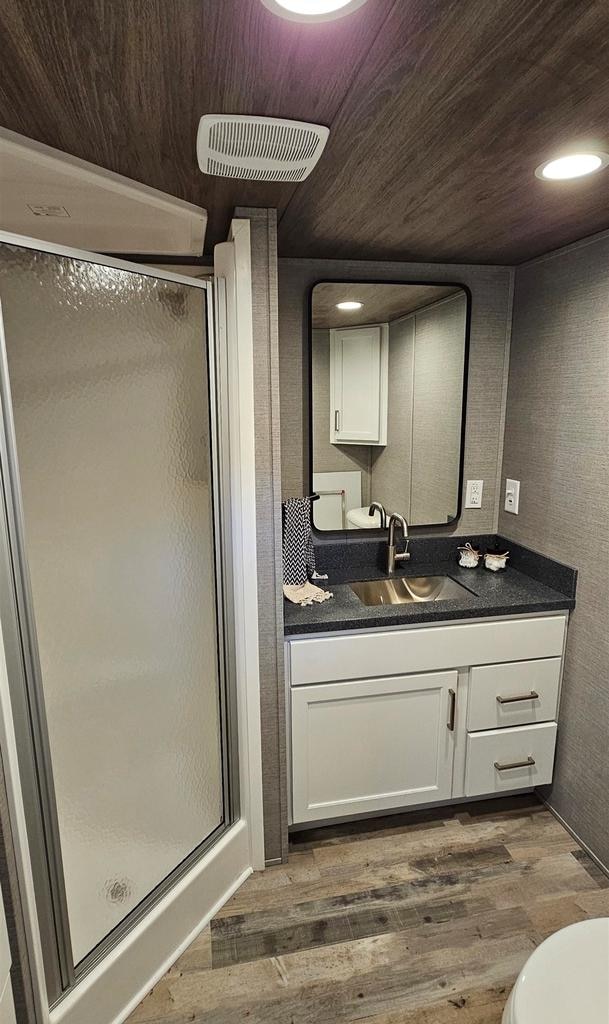 bathroom featuring vanity, an enclosed shower, hardwood / wood-style flooring, wooden ceiling, and toilet