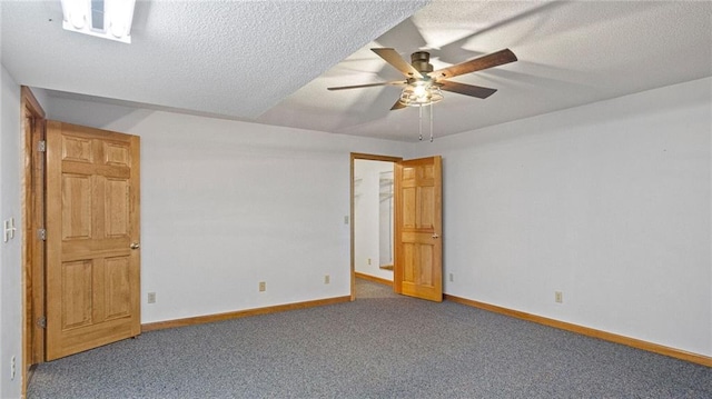 empty room featuring dark carpet, ceiling fan, and a textured ceiling