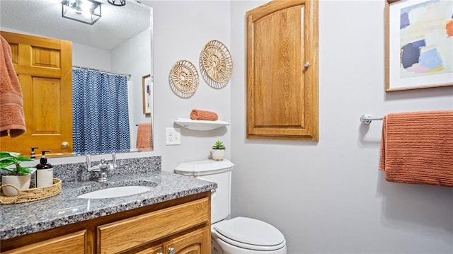 bathroom featuring a textured ceiling, vanity, and toilet