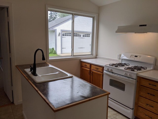 kitchen with light tile patterned floors, ventilation hood, gas range gas stove, and sink