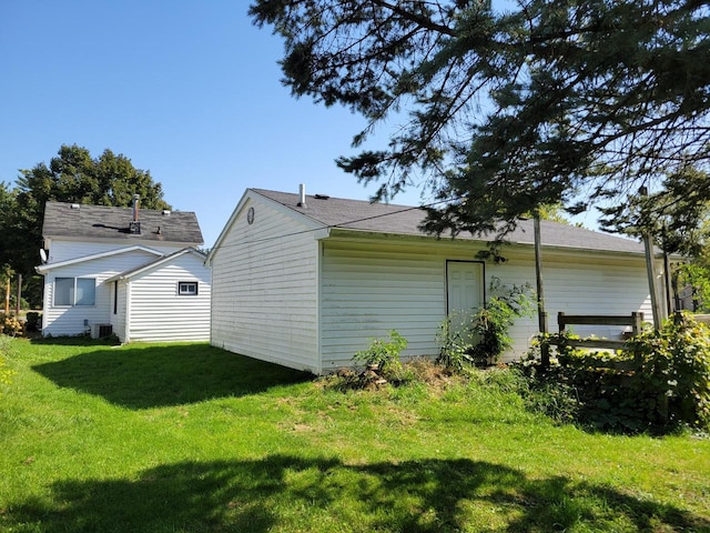 rear view of property featuring central AC unit and a lawn