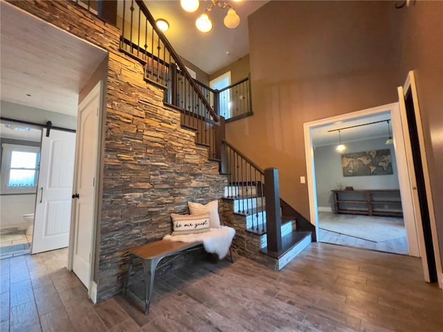 stairway featuring a towering ceiling, hardwood / wood-style floors, and a barn door