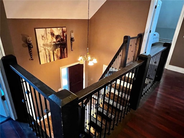 stairs with a chandelier, hardwood / wood-style floors, and high vaulted ceiling