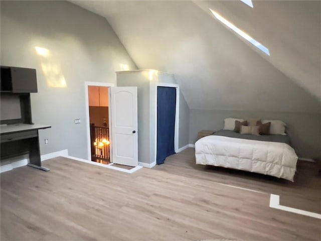 bedroom with vaulted ceiling with skylight and light hardwood / wood-style floors