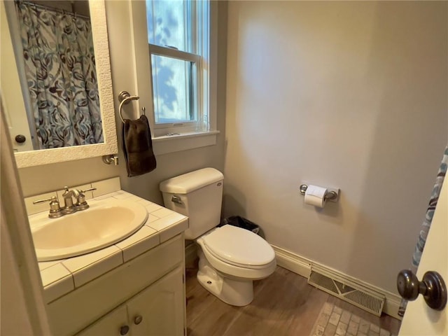 bathroom with wood-type flooring, vanity, and toilet