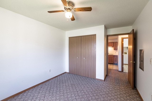 unfurnished bedroom featuring ceiling fan, electric panel, a textured ceiling, carpet, and a closet