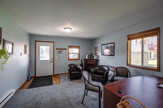 carpeted office featuring a baseboard heating unit and a textured ceiling