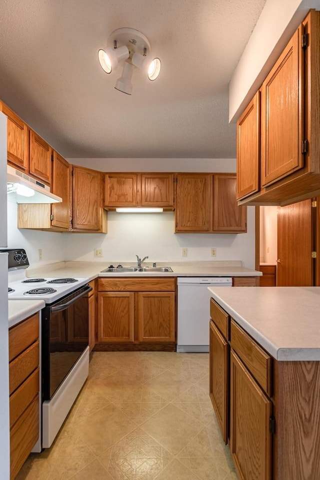 kitchen featuring white appliances, a textured ceiling, and sink