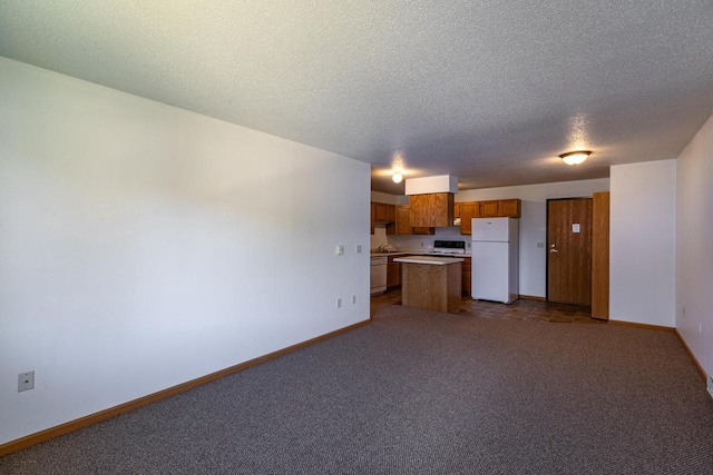 kitchen featuring dark carpet, white appliances, a textured ceiling, and a kitchen island