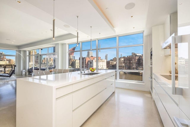 kitchen featuring white cabinets, an island with sink, hanging light fixtures, and sink