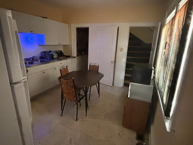 kitchen with white cabinets, sink, and white fridge