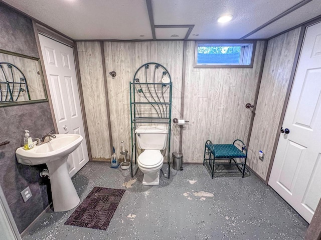 bathroom featuring wooden walls, a textured ceiling, and toilet