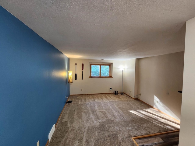 carpeted empty room featuring a textured ceiling