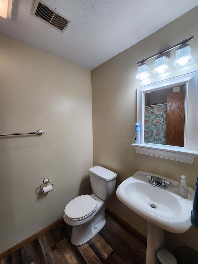 bathroom featuring walk in shower, wood-type flooring, and toilet