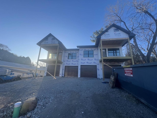 view of front of house featuring an attached garage, gravel driveway, and stucco siding