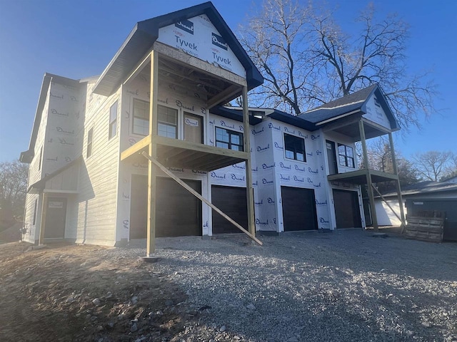 back of property with gravel driveway and a garage