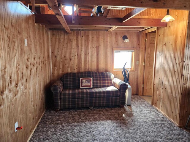 unfurnished room with beam ceiling, carpet, and wooden walls