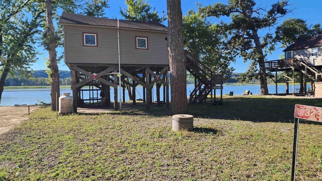 view of dock with a lawn, a water view, and stairway