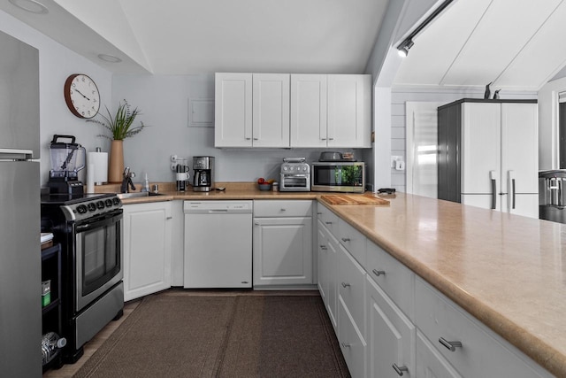 kitchen with sink, appliances with stainless steel finishes, vaulted ceiling, and white cabinetry