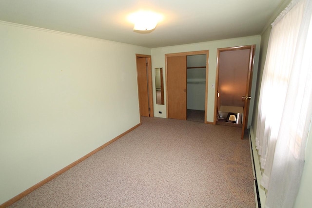 carpeted empty room featuring crown molding and a baseboard heating unit