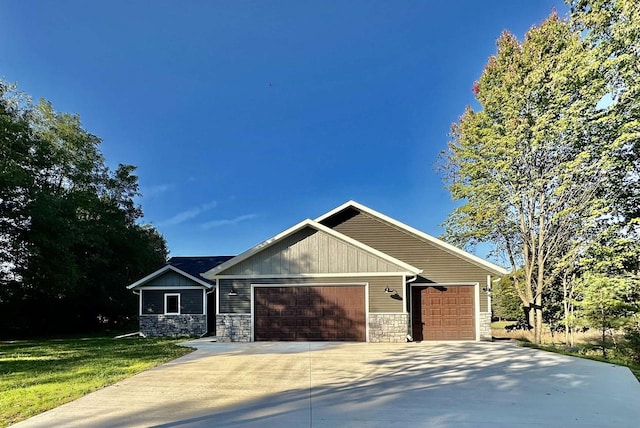 view of front facade featuring a front lawn, an attached garage, stone siding, and driveway