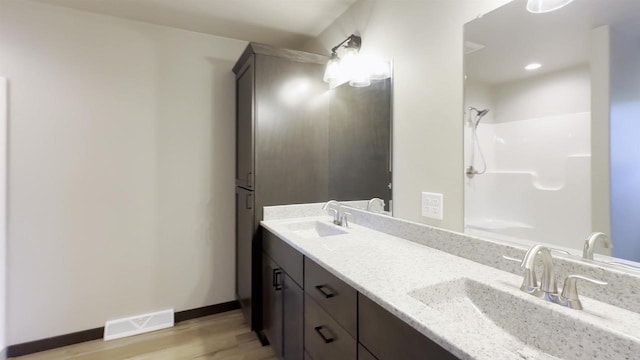 bathroom with a sink, visible vents, a shower, and wood finished floors