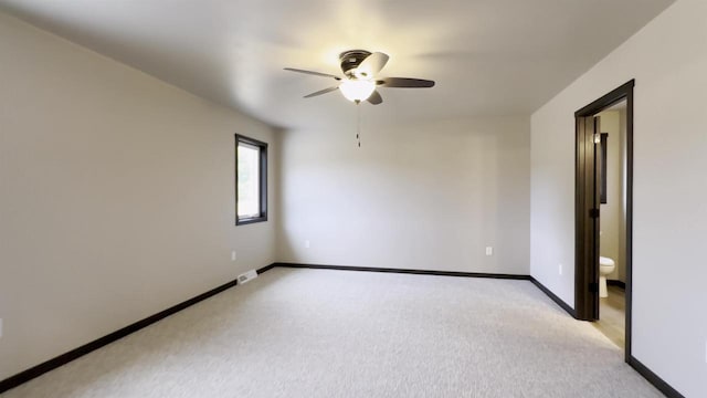 spare room featuring visible vents, light colored carpet, baseboards, and ceiling fan