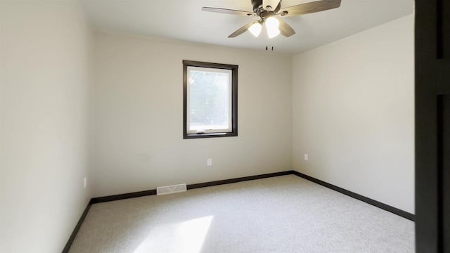 carpeted spare room featuring baseboards, visible vents, and ceiling fan