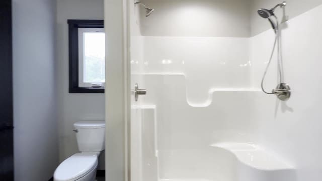 bathroom featuring a stall shower and toilet