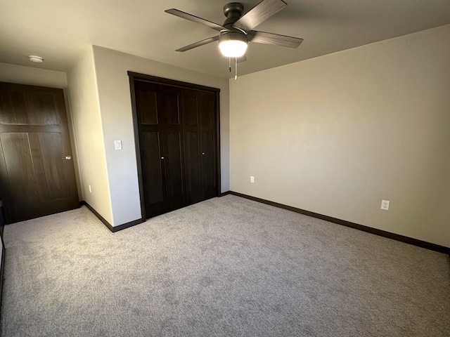 unfurnished bedroom featuring light colored carpet, baseboards, a closet, and ceiling fan