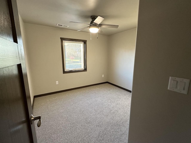 carpeted empty room featuring visible vents, a ceiling fan, and baseboards