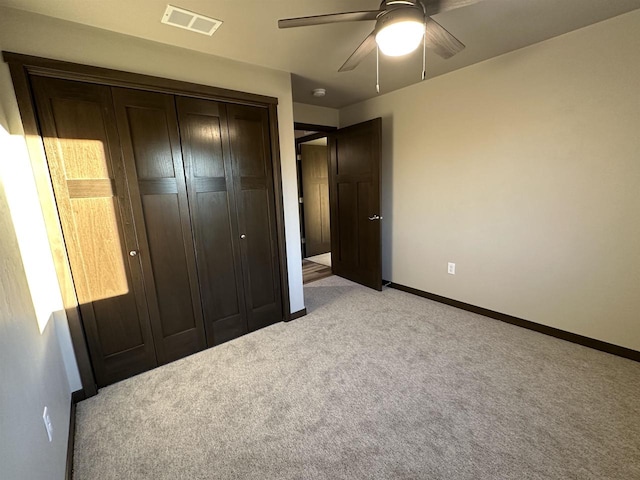 unfurnished bedroom with baseboards, visible vents, light carpet, and a closet