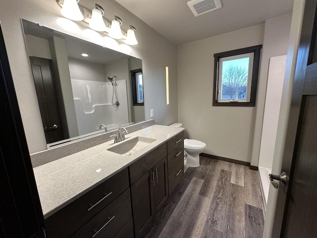 full bathroom with visible vents, toilet, wood finished floors, vanity, and a shower