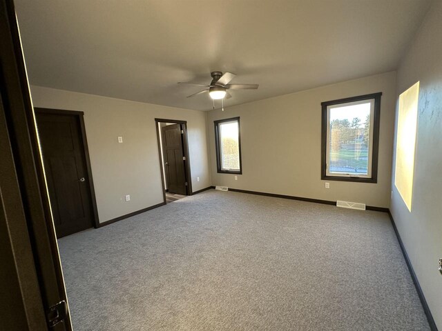 empty room with visible vents, a ceiling fan, baseboards, and carpet floors