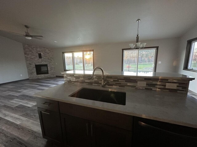 kitchen with tasteful backsplash, a sink, lofted ceiling, a fireplace, and dark wood-style flooring