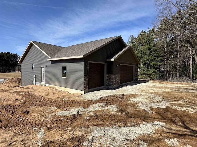 view of home's exterior featuring stone siding and a shingled roof