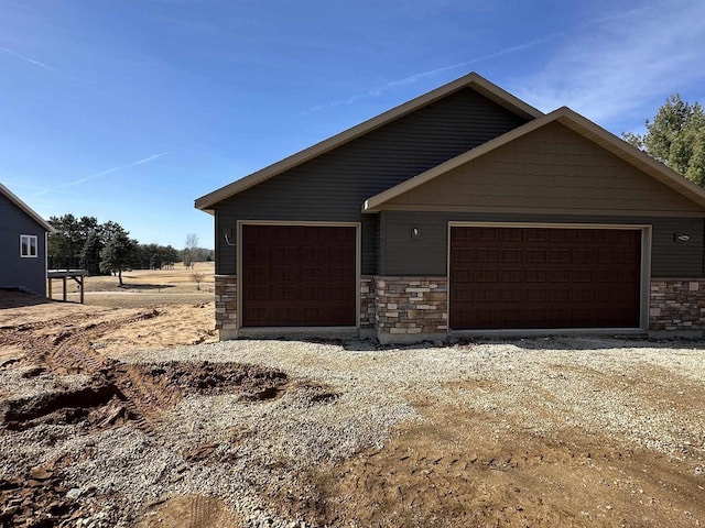 view of front of house featuring stone siding, driveway, and an outdoor structure