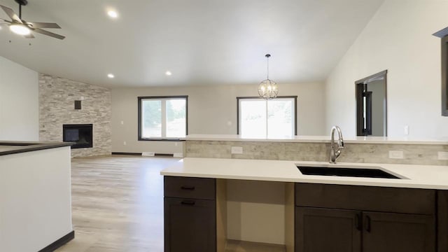 kitchen featuring a sink, a fireplace, light wood finished floors, light countertops, and vaulted ceiling