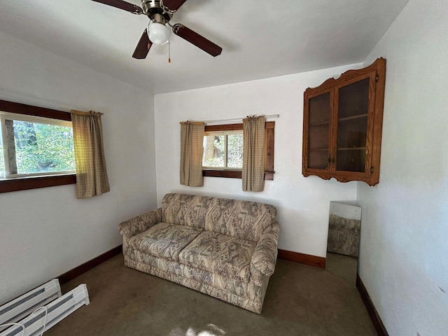 living area featuring ceiling fan, a baseboard radiator, dark carpet, and a healthy amount of sunlight