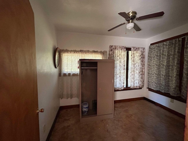 unfurnished bedroom with multiple windows, dark carpet, ceiling fan, and a closet