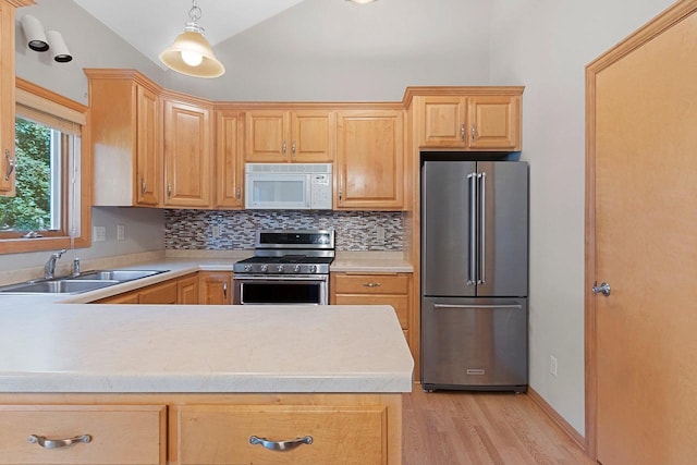 kitchen featuring decorative backsplash, light hardwood / wood-style floors, pendant lighting, stainless steel appliances, and sink